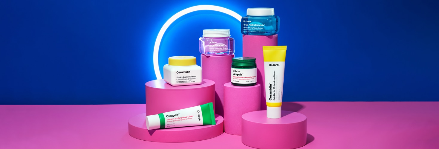 Jars and tubes of Dr.Jart+'s bestselling moisturizers stand tall in front of a bright blue backdrop