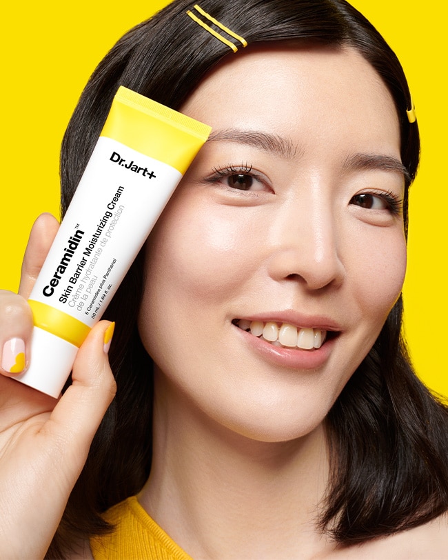 Woman holds tube of Ceramidin Moisturizer Cream in science lab setting