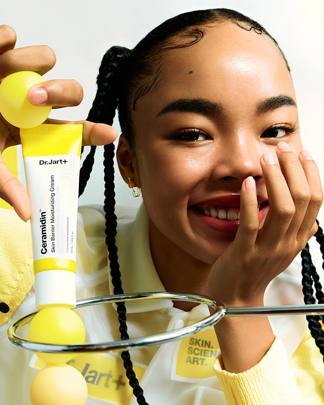 Woman holds tube of Ceramidin Moisturizer Cream in science lab setting