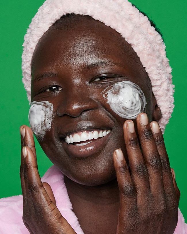 Woman applies Cicapair Face Wash Cleanser to skin showcasing foamy texture