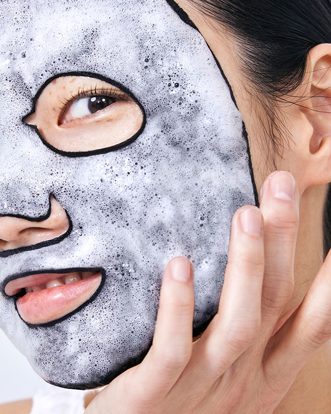 Close up view of charcoal face mask bubbles, foam and texture on skin.