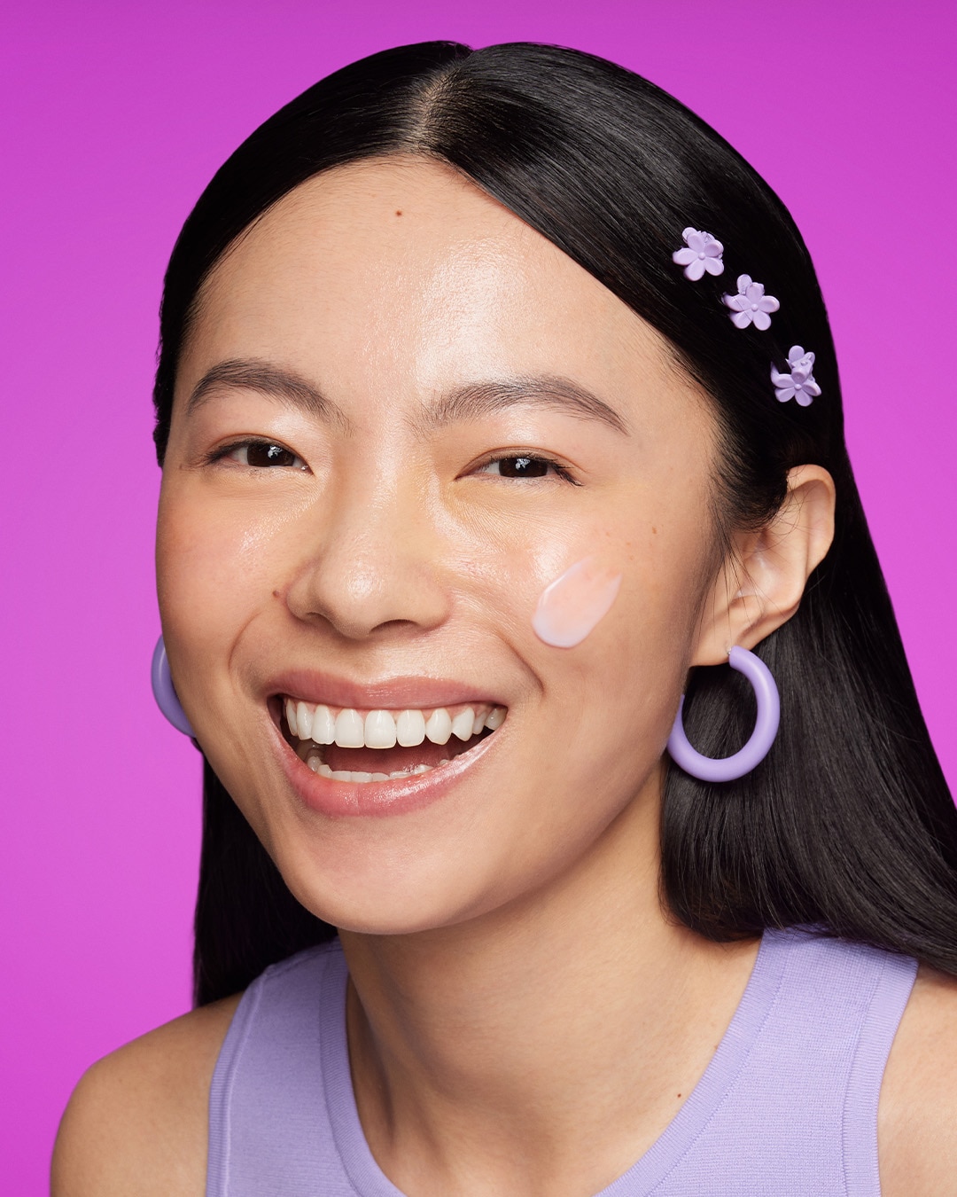 A woman smiles with a dollop of Prejuvenation Serum swiped across her cheek.